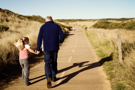 man with small girl walking on the road